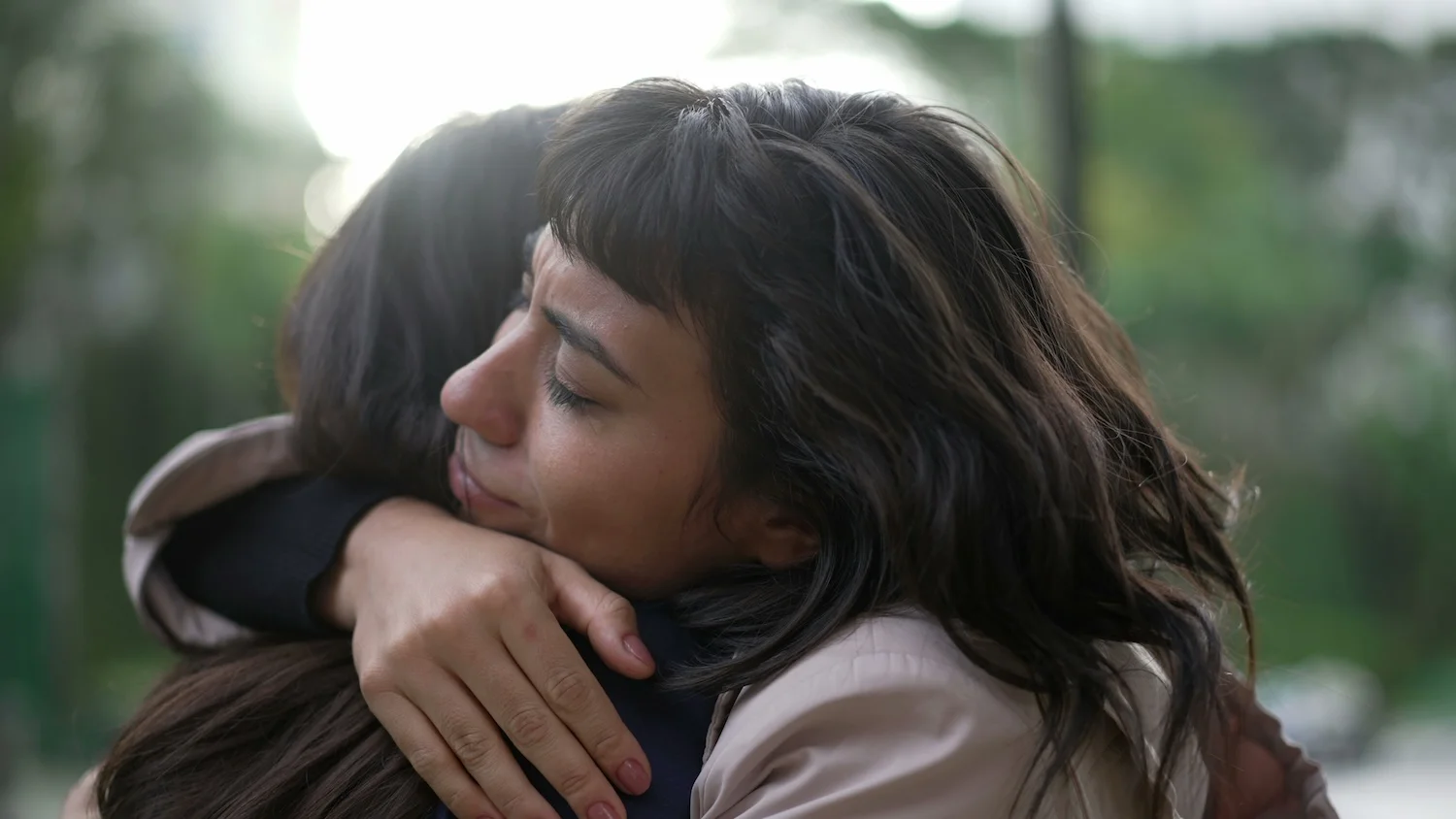 Close-up of two women embracing outdoors, showing emotional support and compassion.