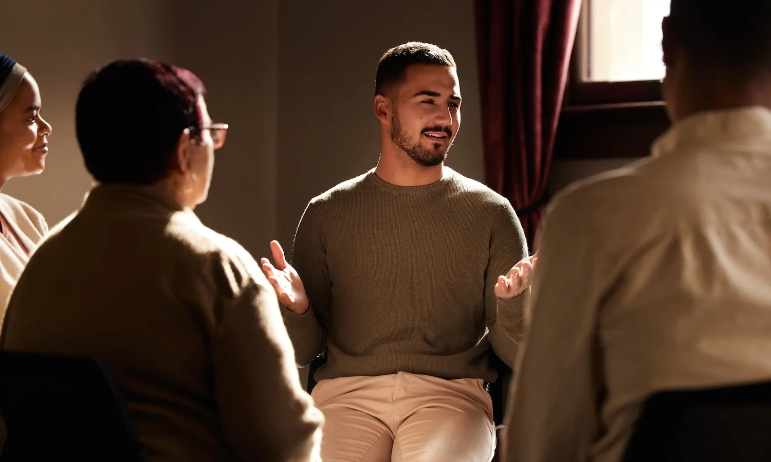 Man sharing and gesturing while participating in a small group therapy session.