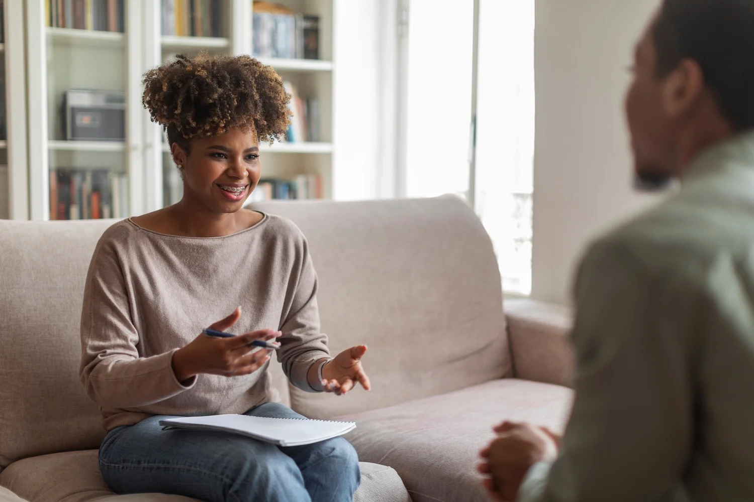 Therapist engaging in conversation with a male client on a couch.