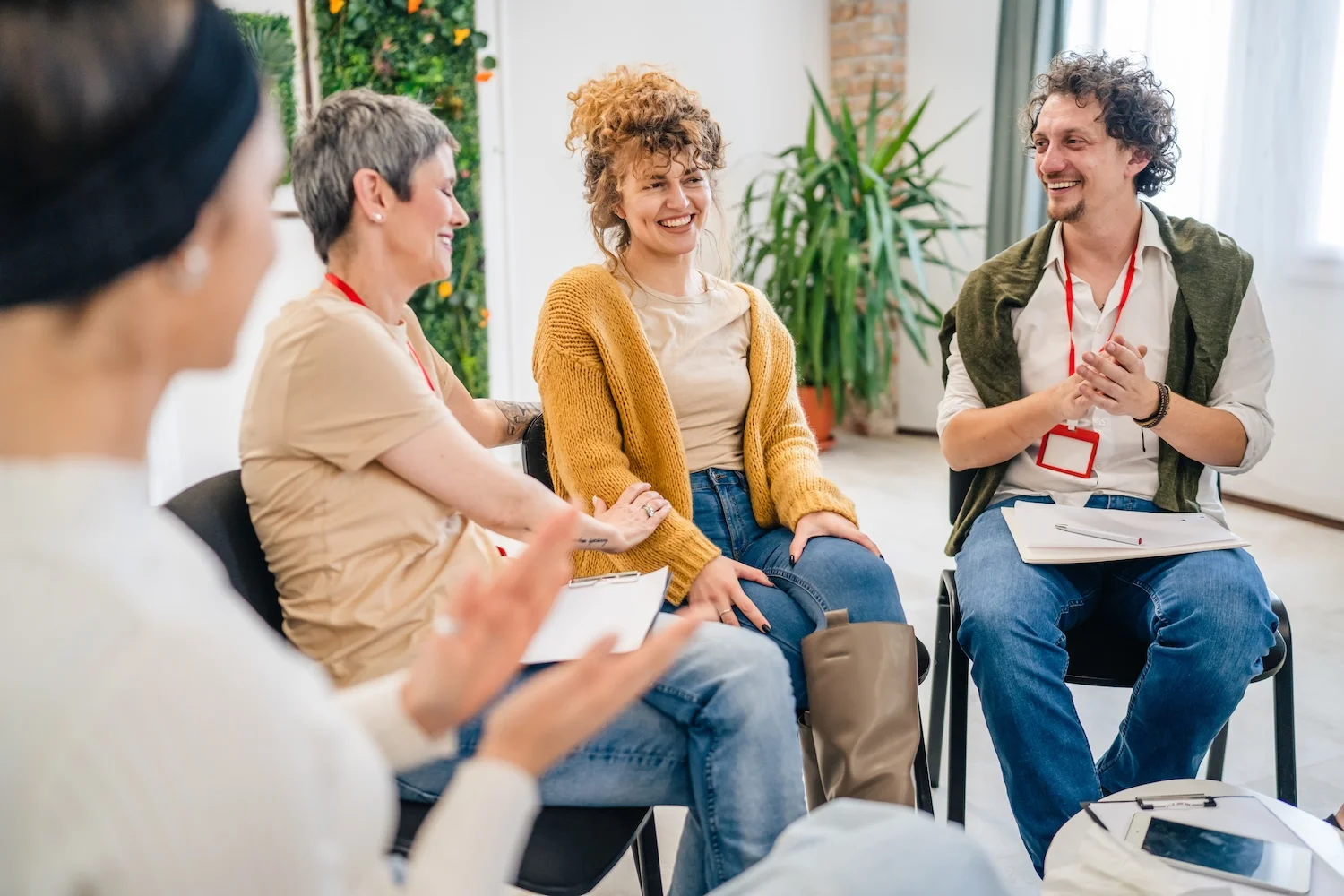 Group therapy participants smiling and supporting each other in a circle.
